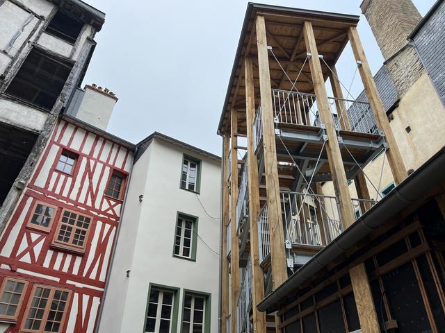 Vue cour arrière immeuble à pans de bois coloré et escalier extérieur